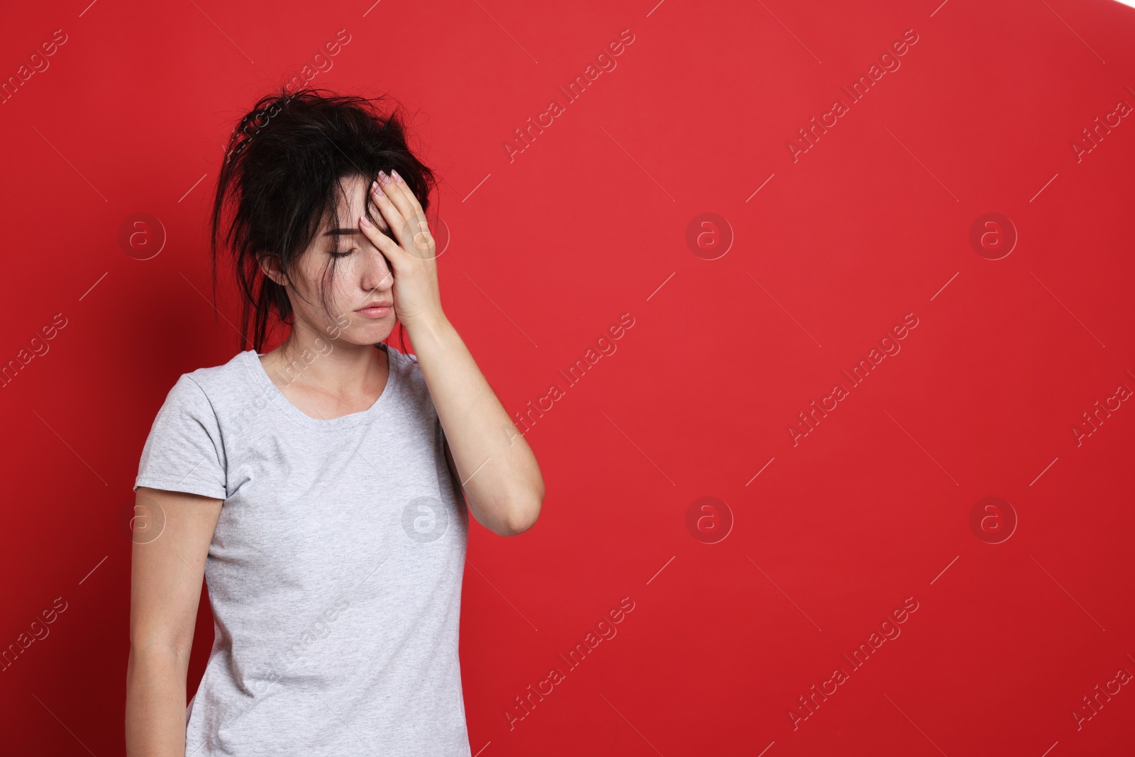 Photo of Woman suffering from hangover on red background, space for text
