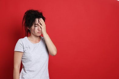 Photo of Woman suffering from hangover on red background, space for text