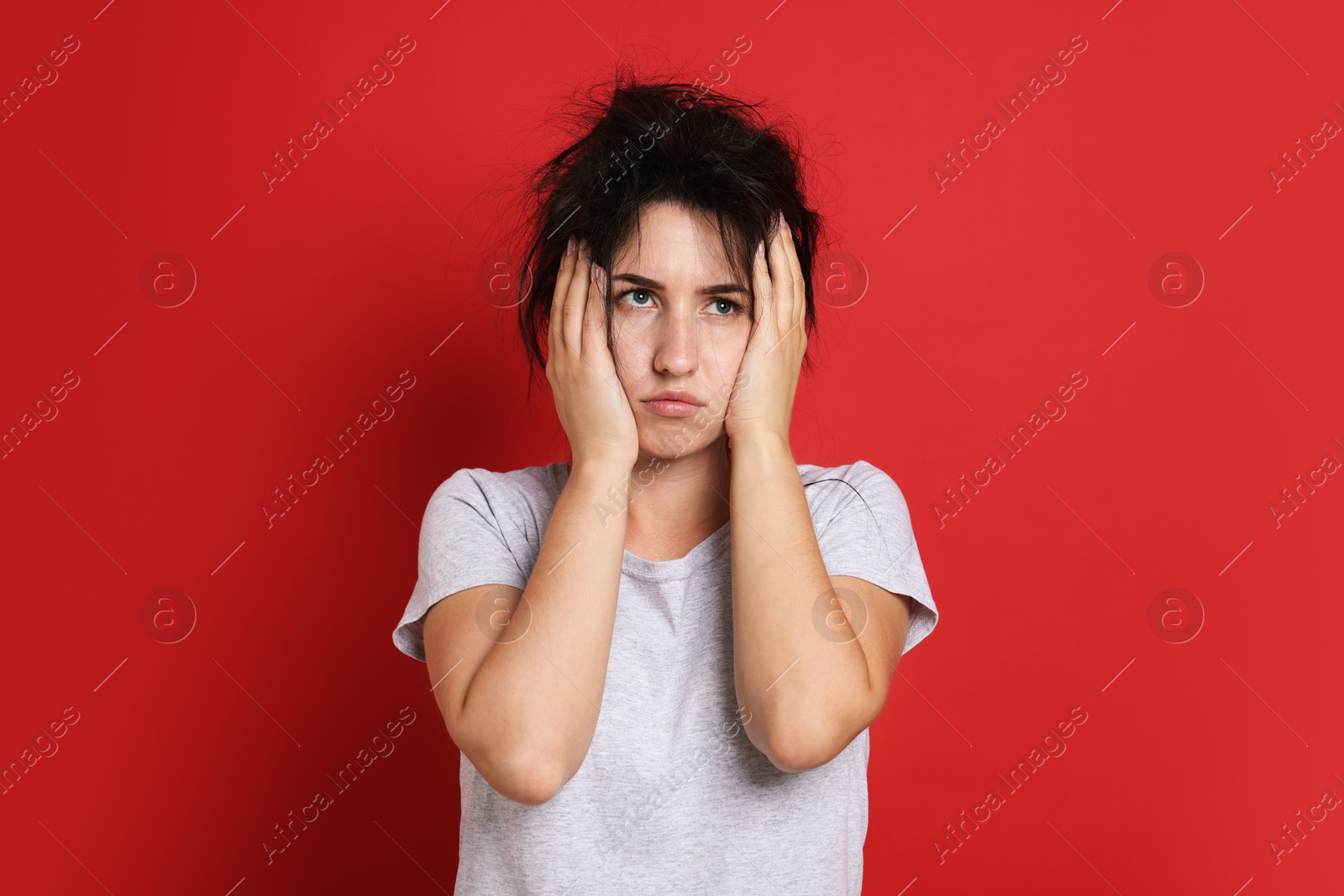 Woman suffering from hangover on red background Photo of Woman suffering from hangover on red background