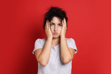 Photo of Woman suffering from hangover on red background
