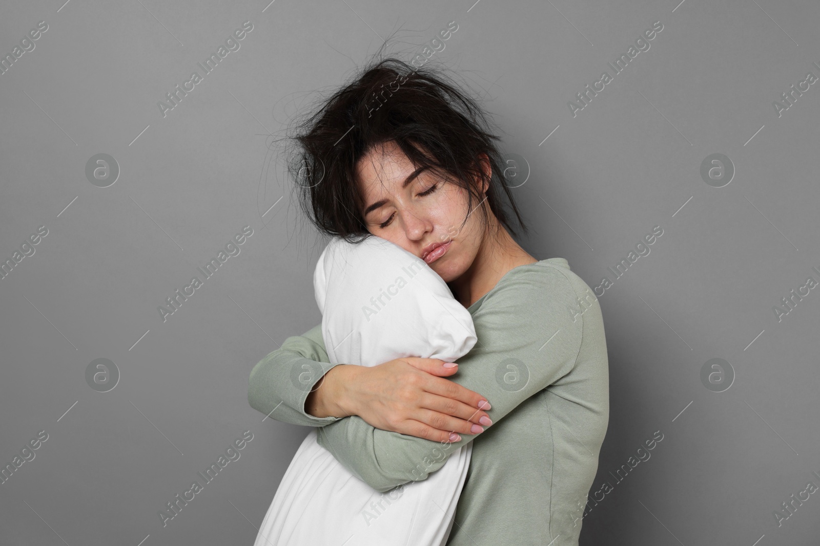 Photo of Woman with pillow suffering from hangover on grey background