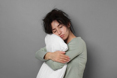 Photo of Woman with pillow suffering from hangover on grey background