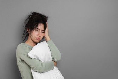 Photo of Woman with pillow suffering from hangover on grey background, space for text