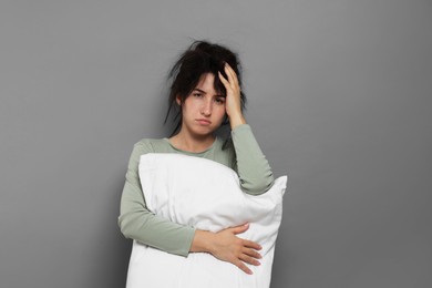 Photo of Woman with pillow suffering from hangover on grey background