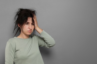 Photo of Woman suffering from hangover on grey background, space for text