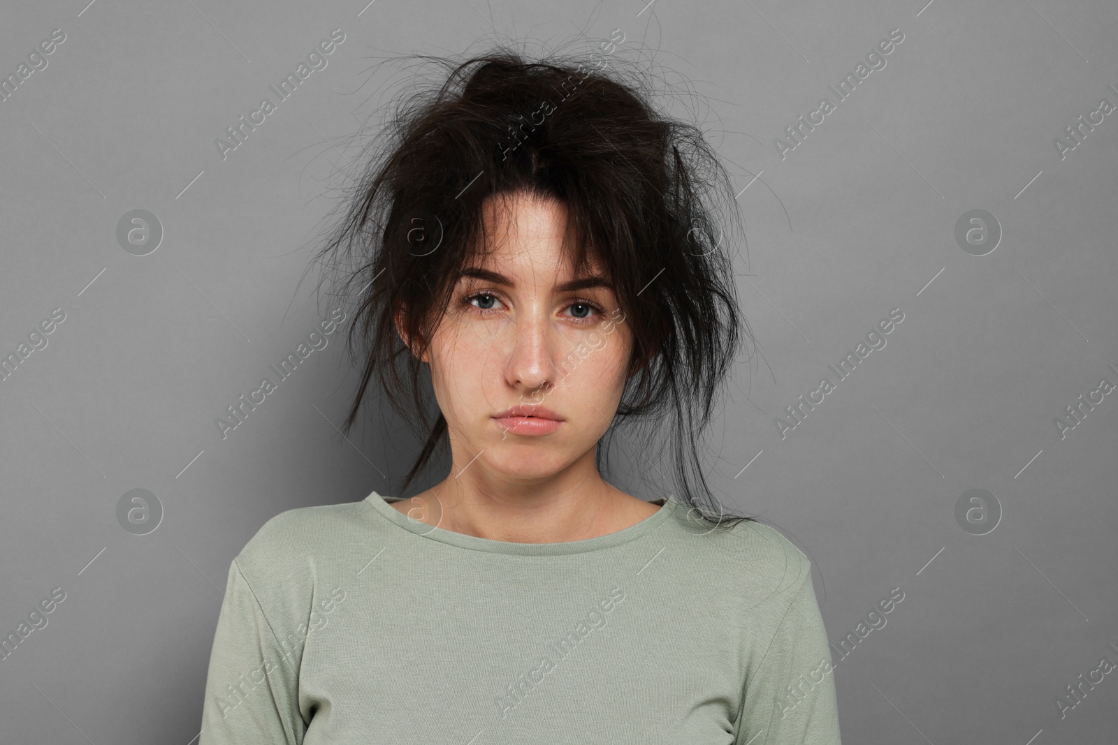 Woman suffering from hangover on grey background Photo of Woman suffering from hangover on grey background