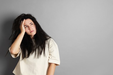 Photo of Woman suffering from hangover on grey background, space for text