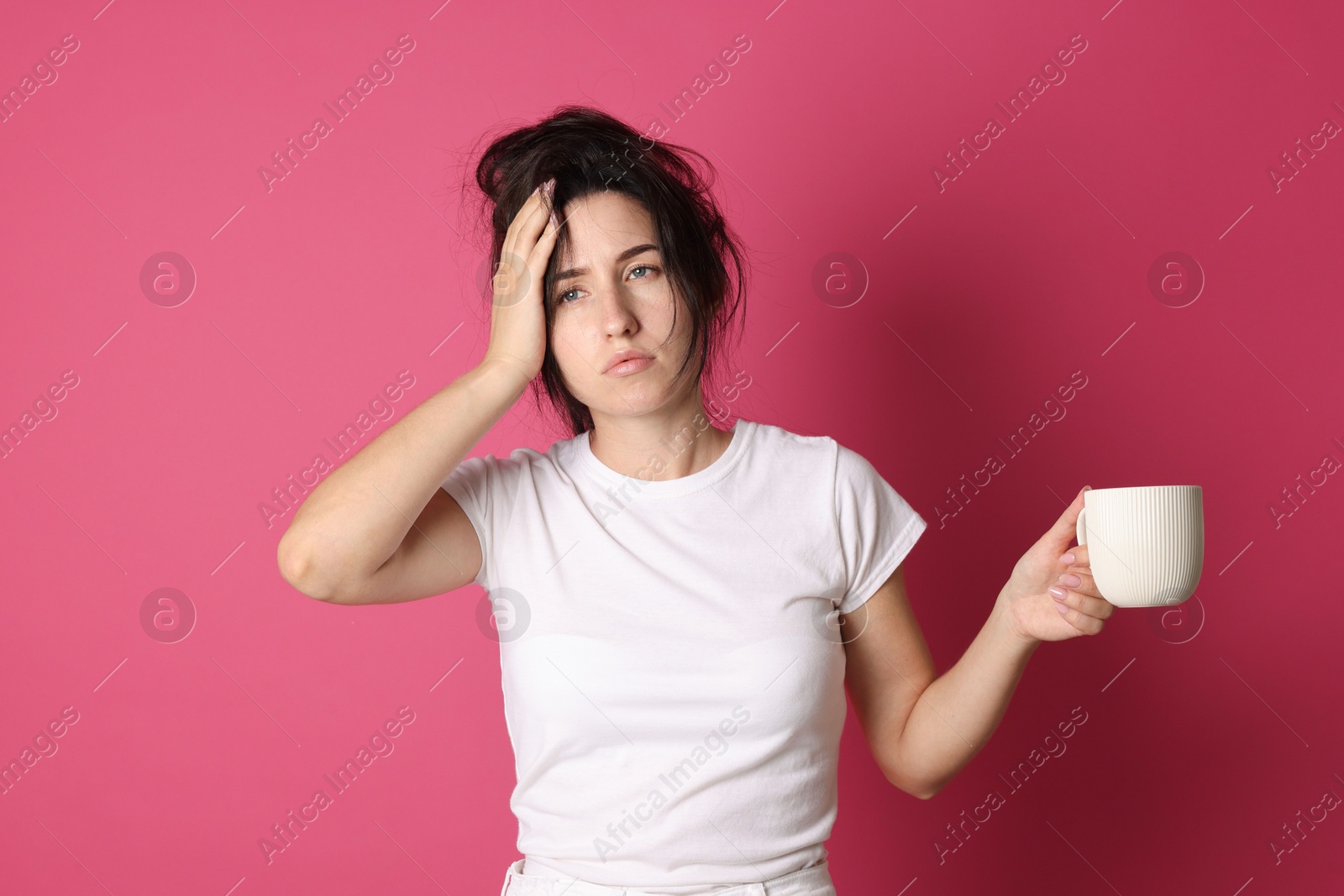 Photo of Woman with cup of drink suffering from hangover on crimson background