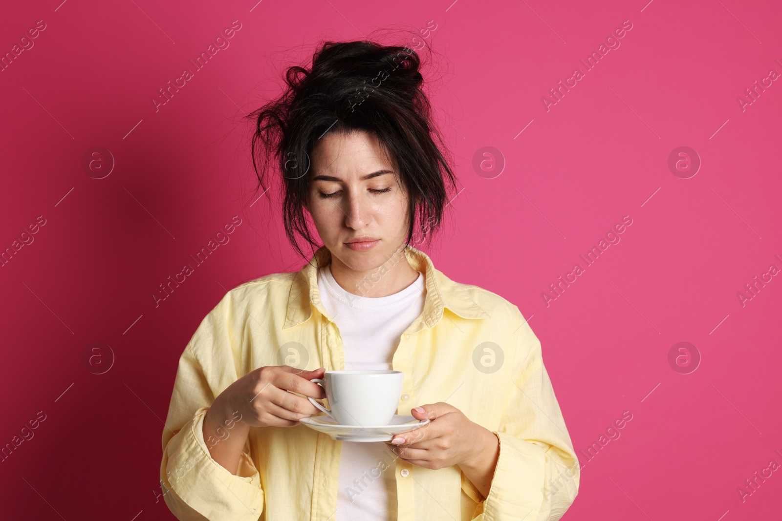 Photo of Woman with cup of drink suffering from hangover on crimson background