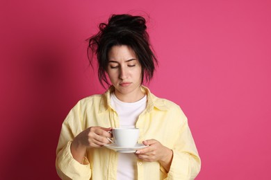 Photo of Woman with cup of drink suffering from hangover on crimson background