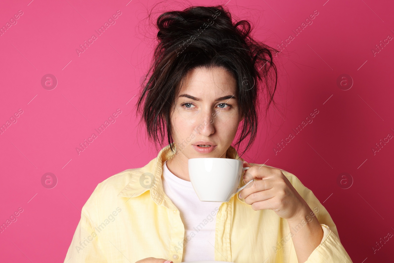 Photo of Woman with cup of drink suffering from hangover on crimson background
