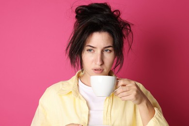 Photo of Woman with cup of drink suffering from hangover on crimson background