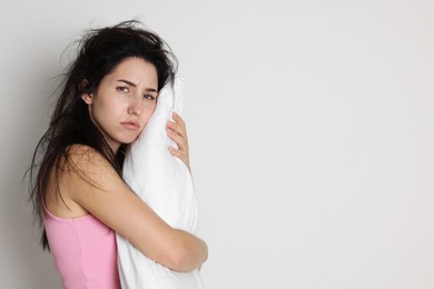 Photo of Woman with pillow suffering from hangover on light grey background, space for text