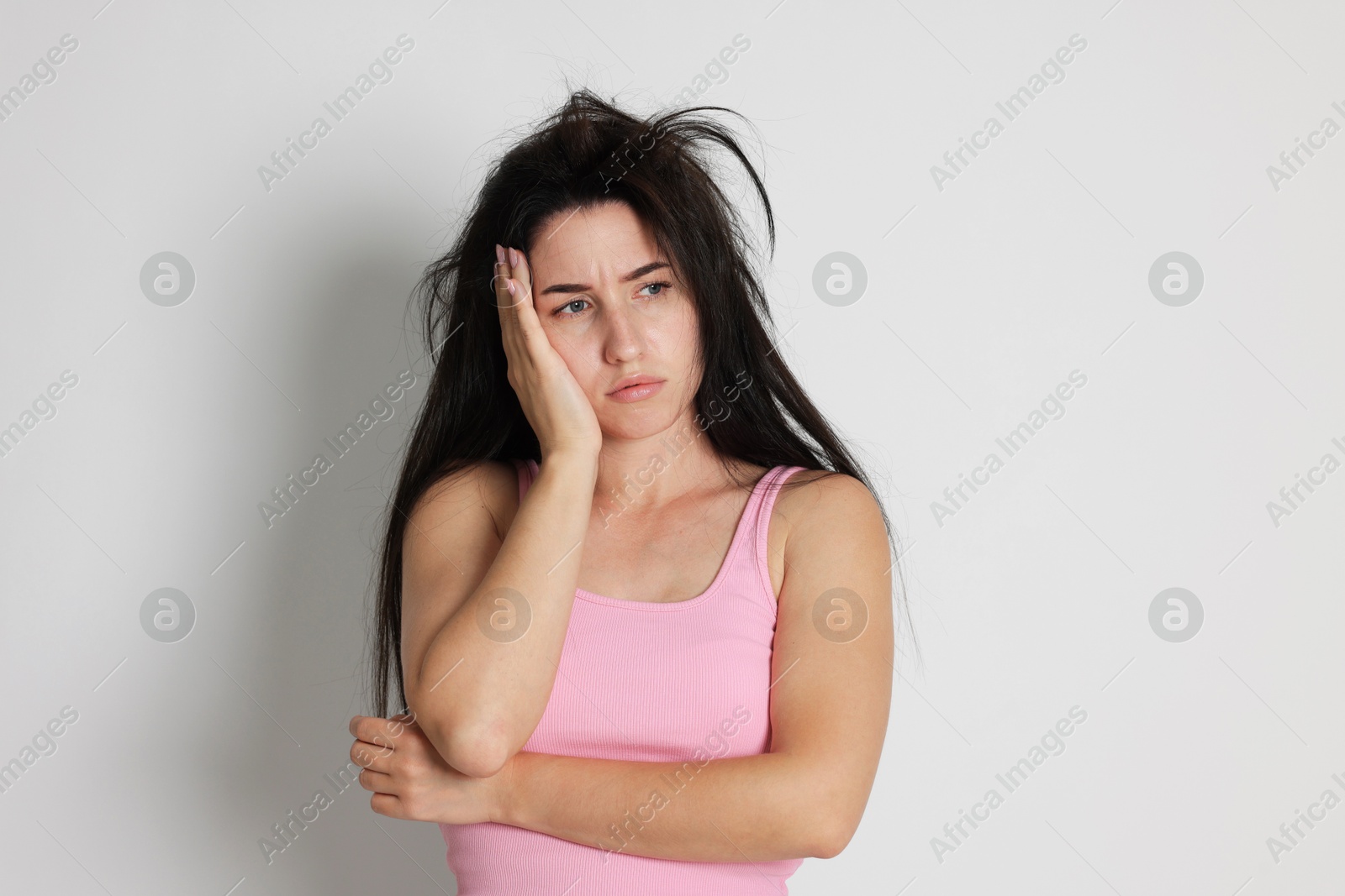 Woman suffering from hangover on light grey background Photo of Woman suffering from hangover on light grey background