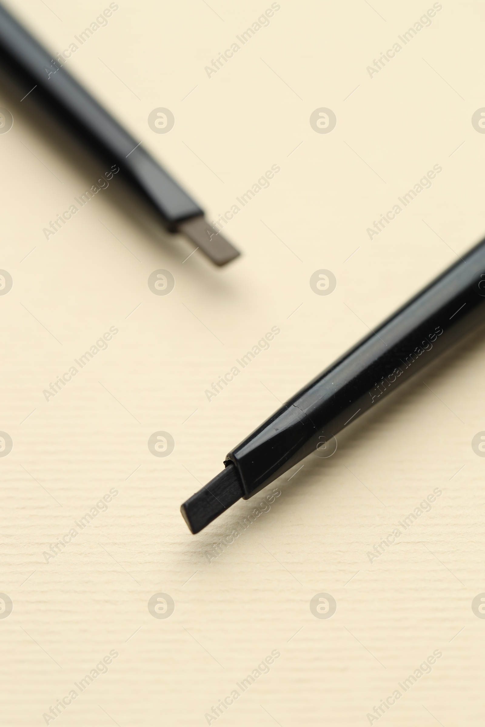 Automatic eyebrow pencils on beige background, macro view Photo of Automatic eyebrow pencils on beige background, macro view
