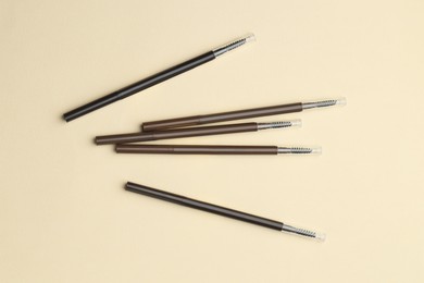 Photo of Automatic eyebrow pencils on beige background, flat lay