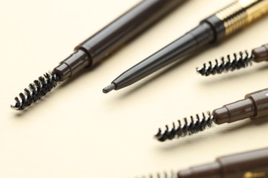 Photo of Automatic eyebrow pencils on beige background, closeup