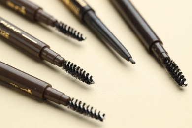 Photo of Automatic eyebrow pencils on beige background, closeup