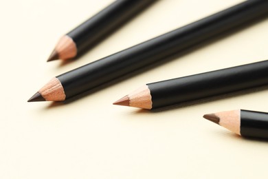 Photo of Different eyebrow pencils on beige background, closeup
