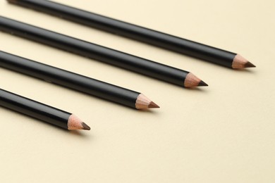Photo of Different eyebrow pencils on beige background, closeup