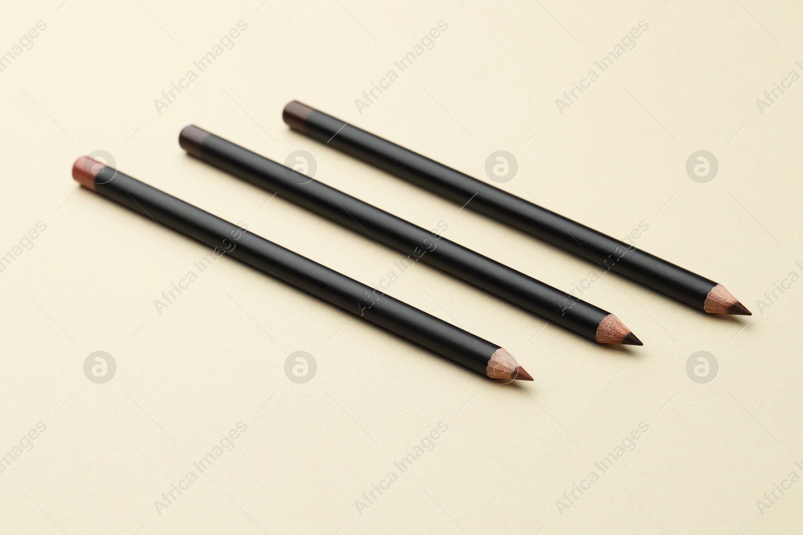 Different eyebrow pencils on beige background, closeup Photo of Different eyebrow pencils on beige background, closeup