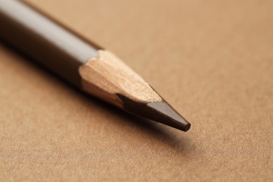 Photo of One eyebrow pencil on brown background, macro view
