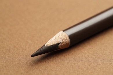 Photo of One eyebrow pencil on brown background, macro view