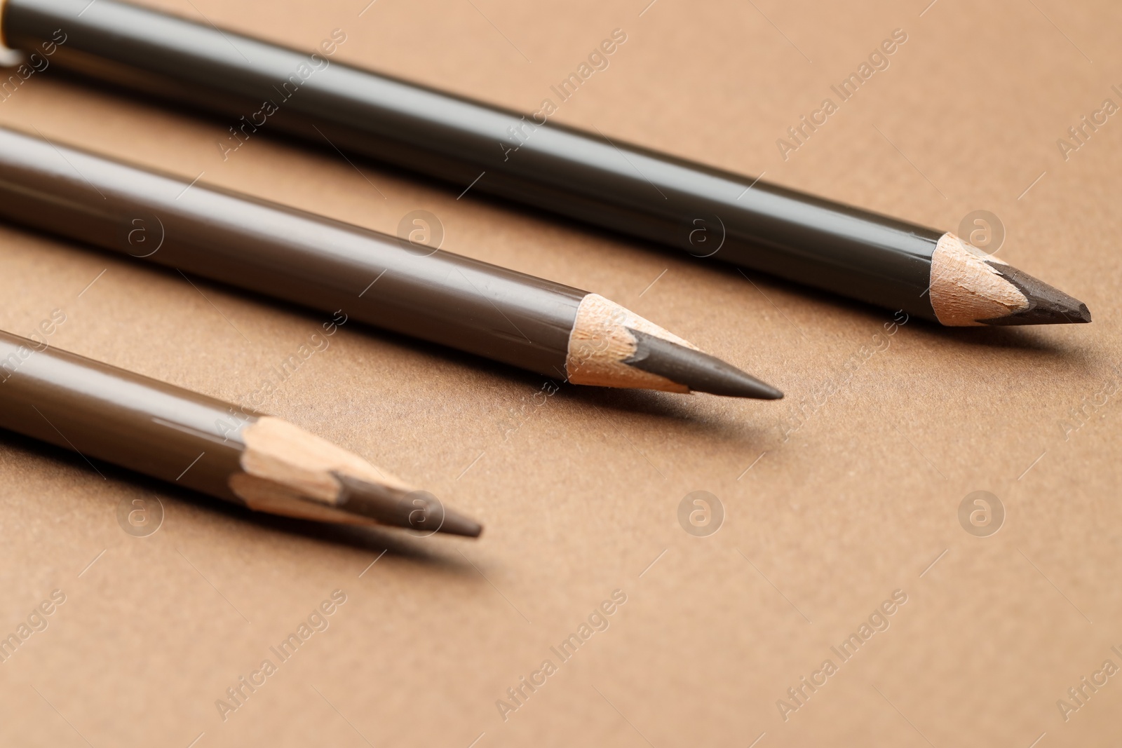 Different eyebrow pencils on brown background, closeup Photo of Different eyebrow pencils on brown background, closeup