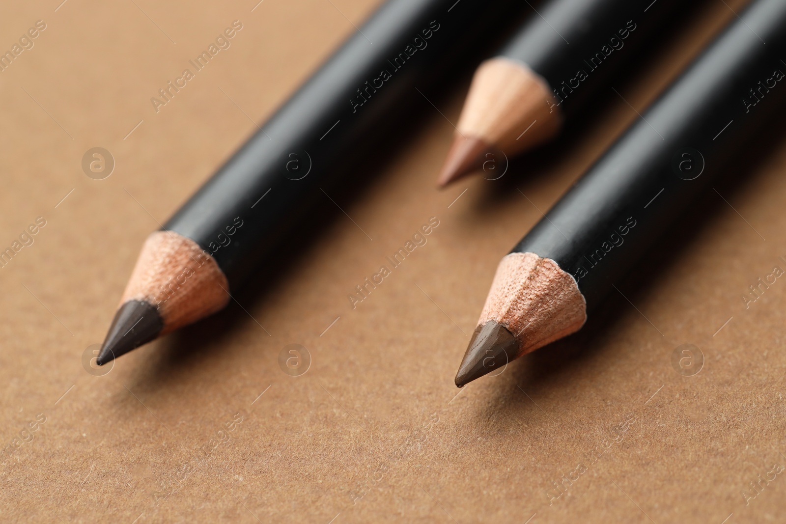Different eyebrow pencils on brown background, closeup Photo of Different eyebrow pencils on brown background, closeup
