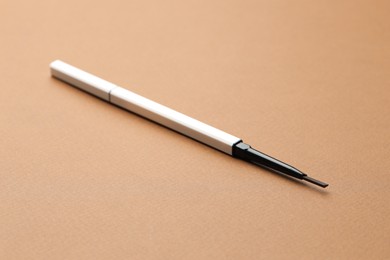Photo of One automatic eyebrow pencil on brown background, closeup