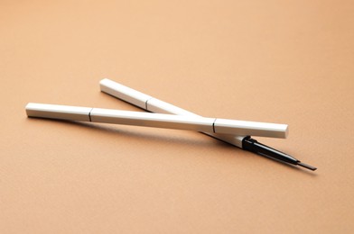 Photo of Automatic eyebrow pencils on brown background, closeup