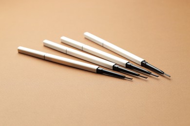Photo of Automatic eyebrow pencils on brown background, closeup