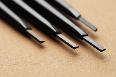 Photo of Automatic eyebrow pencils on brown background, macro view