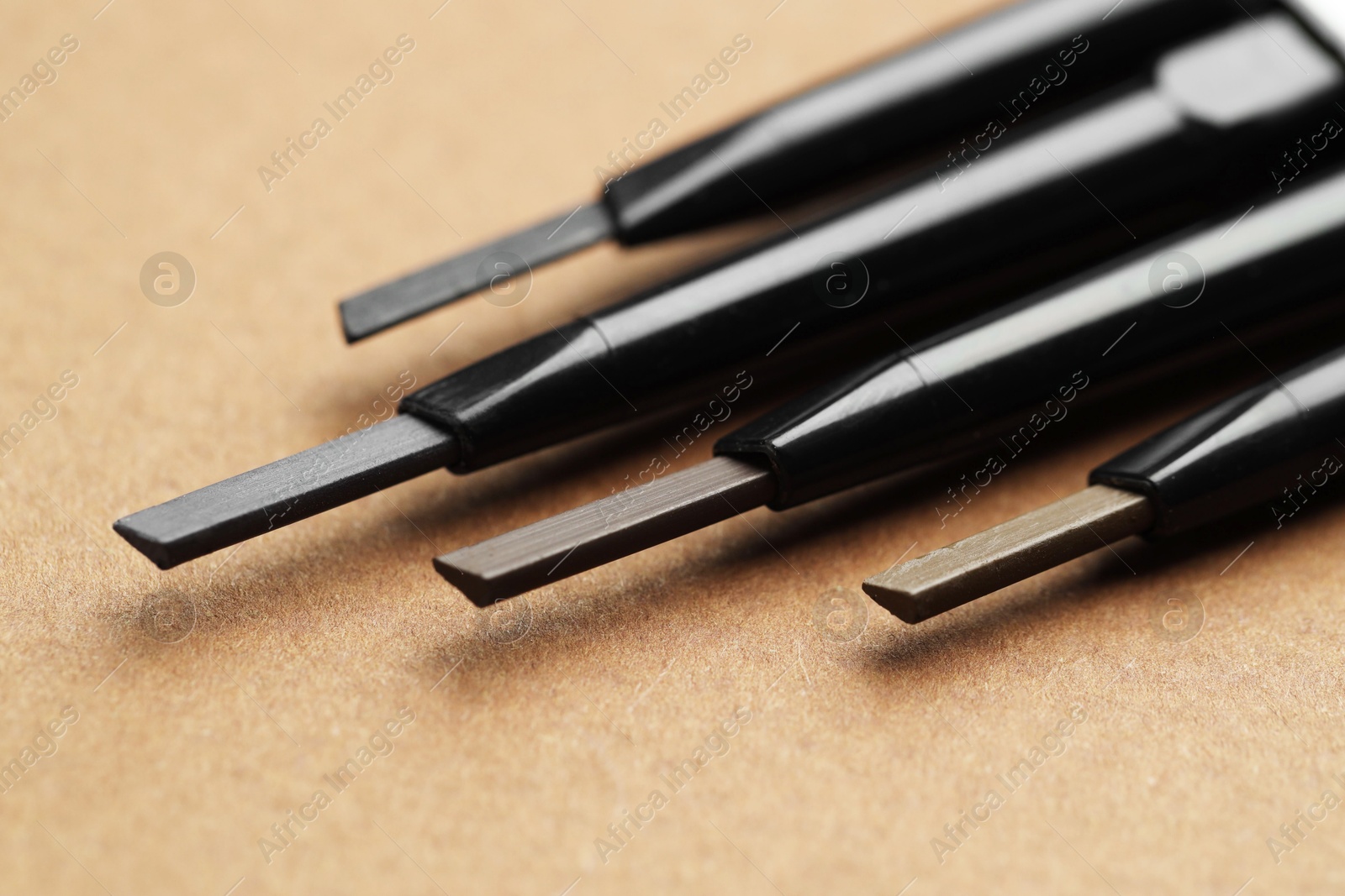 Automatic eyebrow pencils on brown background, macro view Photo of Automatic eyebrow pencils on brown background, macro view