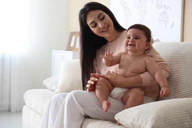 Photo of Happy mother with her cute little baby at home, space for text