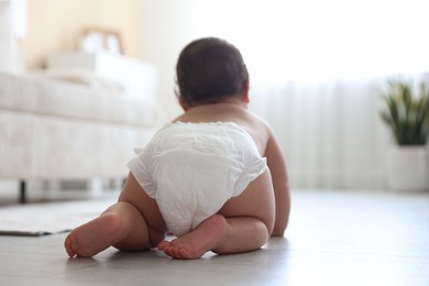Photo of Cute little baby crawling on floor at home, back view