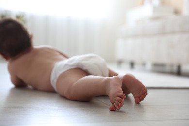 Photo of Cute little baby crawling on floor at home, selective focus