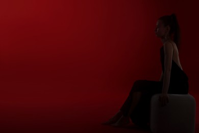 Photo of Silhouette of woman on dark red background, space for text
