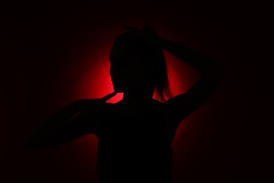Photo of Silhouette of woman on dark red background