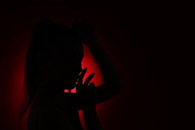 Photo of Silhouette of woman on dark background, space for text
