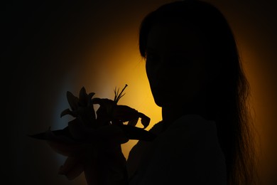 Photo of Silhouette of woman with flowers on dark background