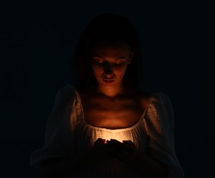 Photo of Woman with light near her chest on black background