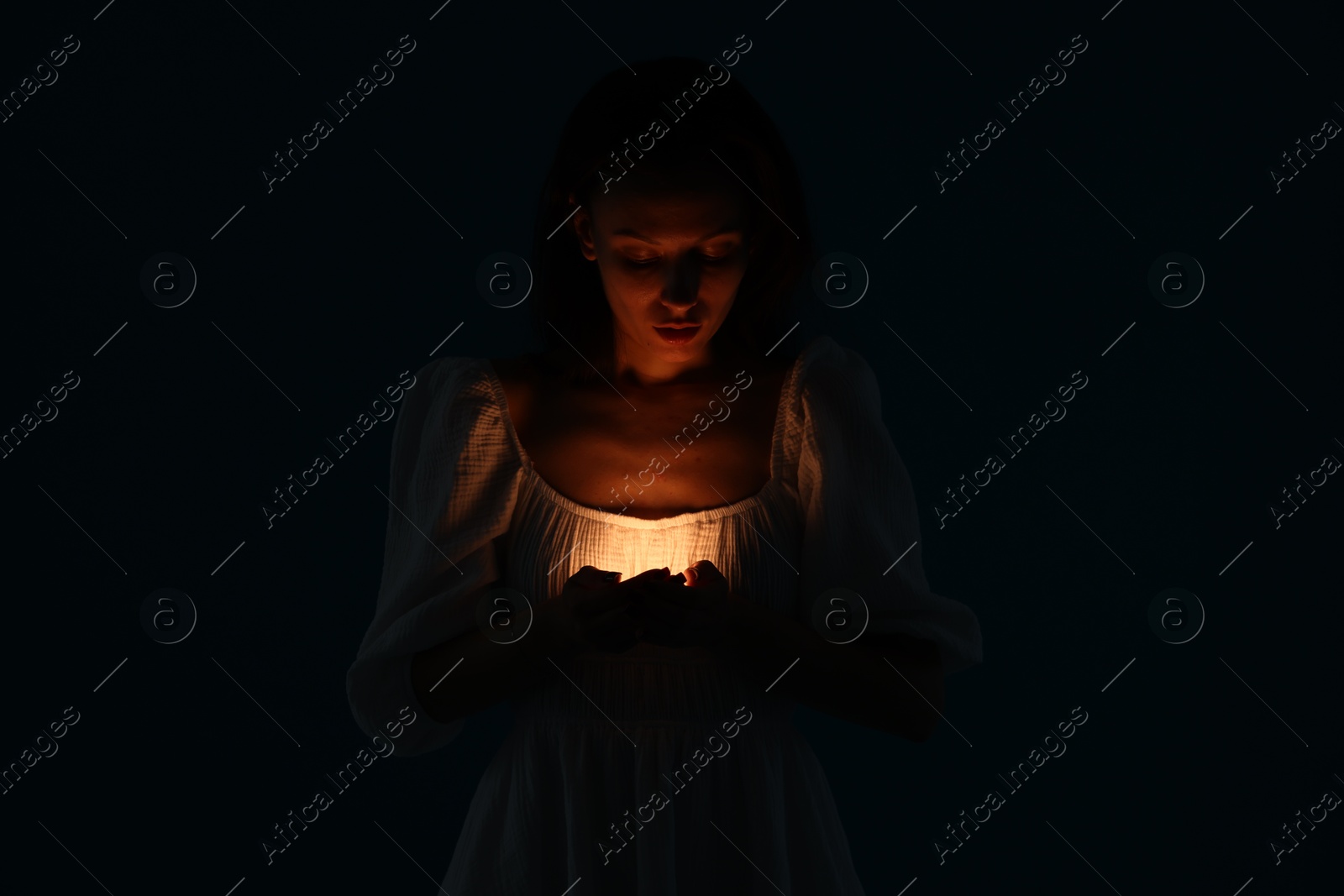 Photo of Woman with light near her chest on black background