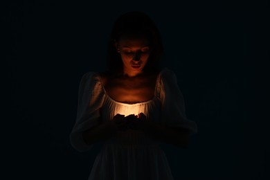 Photo of Woman with light near her chest on black background