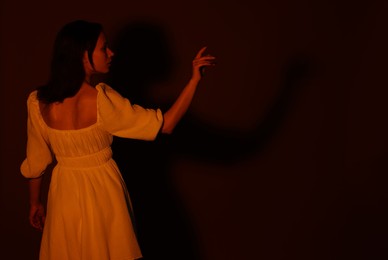 Photo of Woman in dress on dark brown background, back view. Space for text