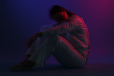 Photo of Beautiful woman sitting on color background, long-exposure