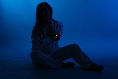 Photo of Silhouette of woman with light near her chest dark blue background