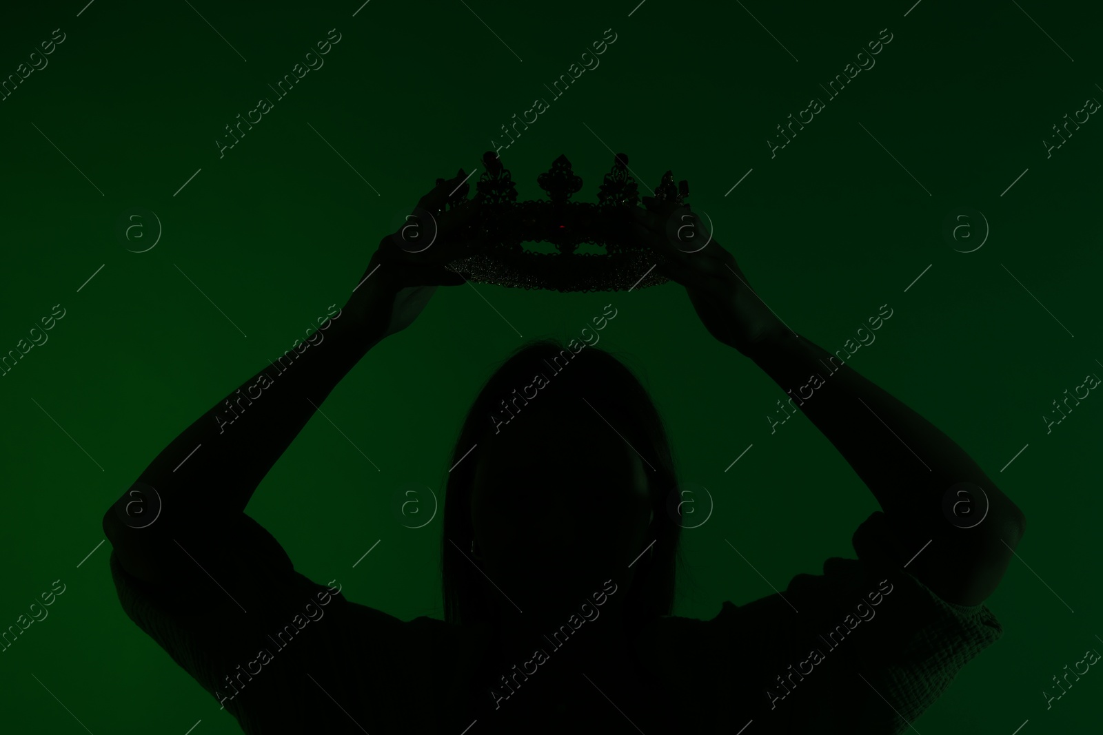 Photo of Silhouette of woman with crown on dark green background