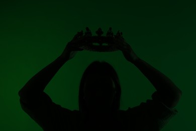 Photo of Silhouette of woman with crown on dark green background