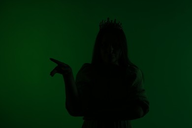 Photo of Silhouette of woman with crown on dark green background